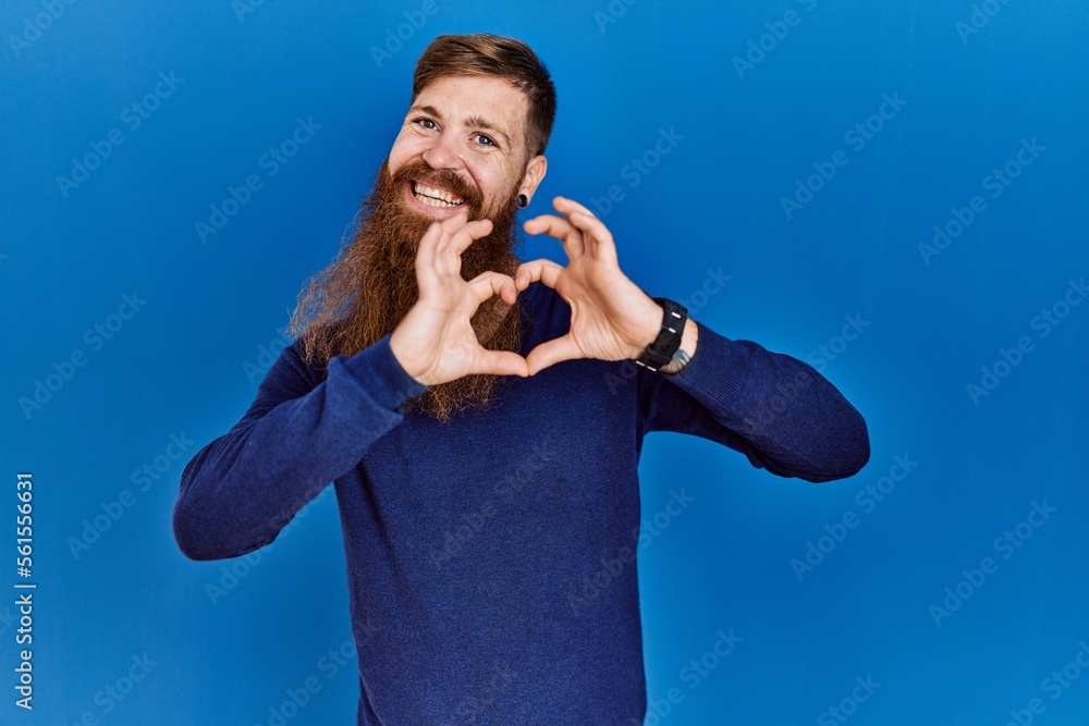 Sticker redhead man with long beard wearing casual blue sweater over blue background smiling in love doing h