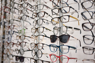 A lot of glasses on display in optical store. Many eyeglass and sunglasses for sale.  