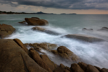 Artistic seascape with blurry waves crashing against granite rocks on the shore, Samui, Thailand