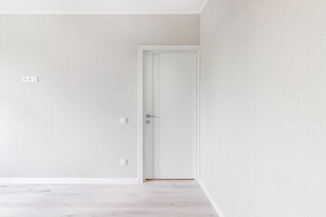 Modern white door. Grey wall with free space. Minimalist bright interior