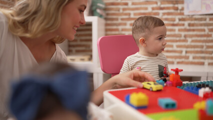 Teacher and preschool student playing with car toy sitting on table at kindergarten