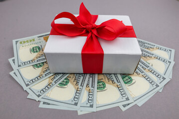 Gift box and dollar bills on gray background