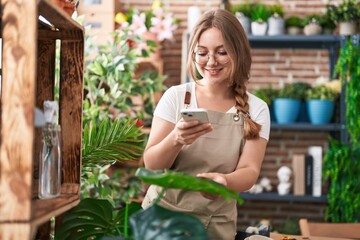Young blonde woman florist taking picture of plants at florist