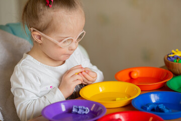 Beautiful smart girl with Down syndrome learns to sort by colors