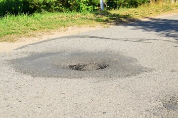Large hole on new asphalt on a summer day