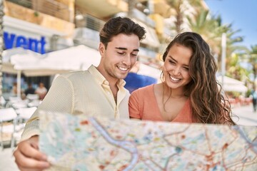 Fototapeta na wymiar Man and woman couple smiling confident holding map at street