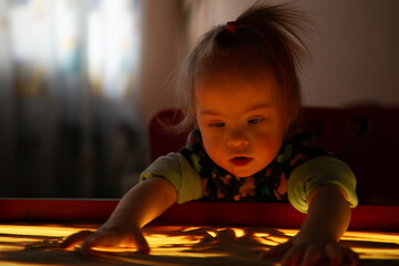 A girl with Down syndrome plays with kinetic sand