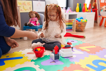 Adorable redhead girl playing money game sitting on floor at kindergarten