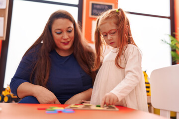 Teacher and student playing with maths puzzle game at kindergarten