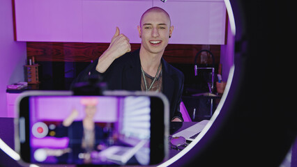 Young male blogger recording himself with smartphone indoor. High quality photo