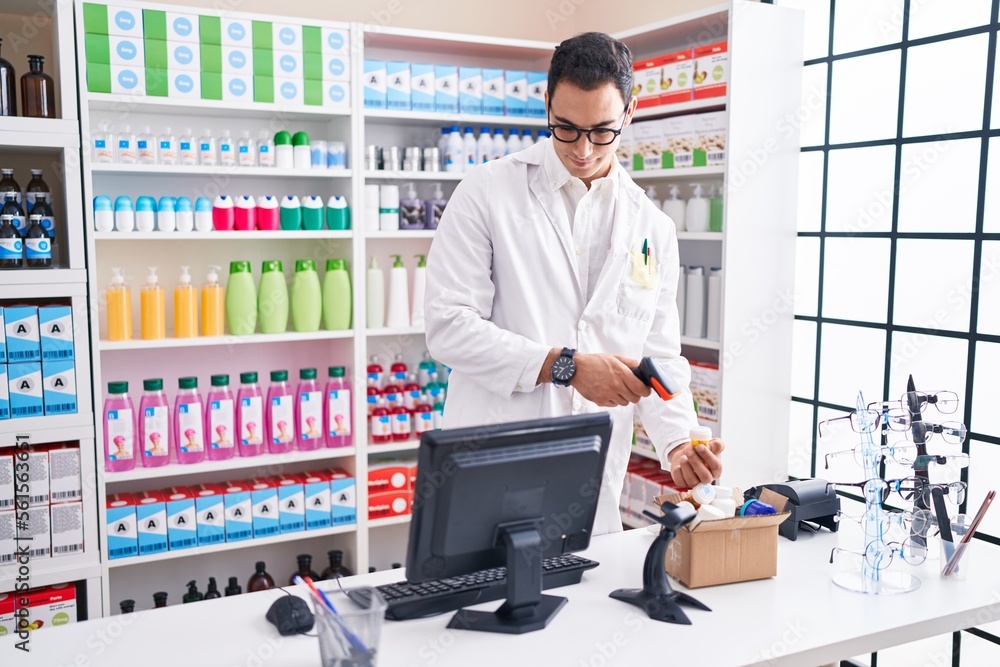 Sticker Young hispanic man pharmacist scanning pills bottle at pharmacy