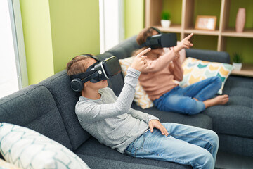 Two kids playing video game using virtual reality glasses at home