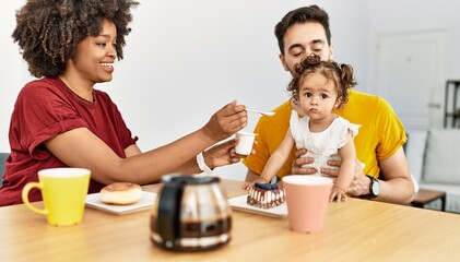 Couple and daughter having breakfast sitting on table at home
