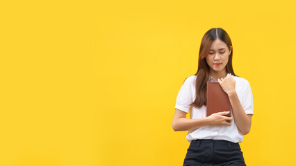 Women are holding holy bible and praying to god with empty space on isolated yellow background