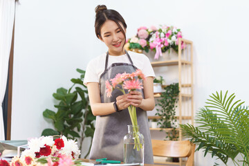 Florist concept, Female florist arranging pink gerbera in vase with happiness at flower shop