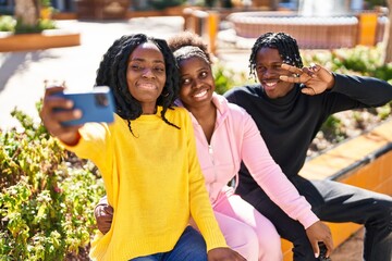 African american friends making selfie by the smartphone sitting on bench at park