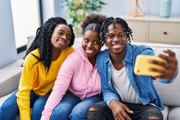 African american friends make selfie by the smartphone sitting on sofa at home