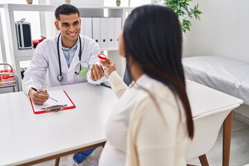 Fototapeta premium Young latin couple doctor and patient having medical session holding urine test tube at clinic