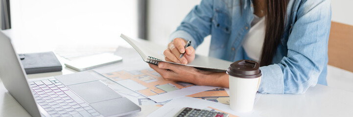 Construction design concept, Female architect taking notes while working about house plan on laptop