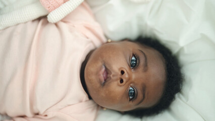 African american baby lying on bed with relaxed expression at bedroom