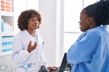 African american women pharmacist and customer holding pills bottle speaking at pharmacy