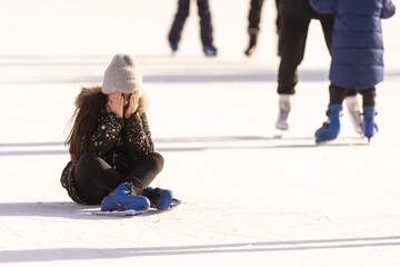 people, sport, trauma, pain and leisure concept - young woman fell down on outdoor skating rink and holding to her knee © Angelov