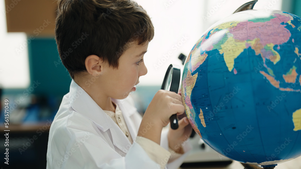 Poster Adorable hispanic boy student looking earth using magnifying glass at laboratory classroom