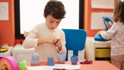 Adorable hispanic boy playing with toys standing at kindergarten