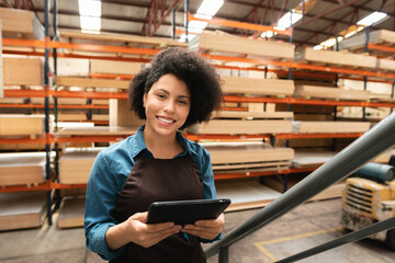 happy female worker looking at camera with tablet at warehouse