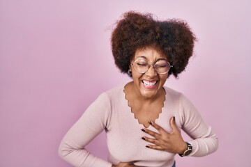 Fototapeta na wymiar Young african american woman standing over pink background smiling and laughing hard out loud because funny crazy joke with hands on body.