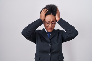 Beautiful african woman with curly hair wearing business jacket and glasses suffering from headache desperate and stressed because pain and migraine. hands on head.