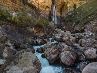 a stream of water flows down from a cave in the high rocks of the Caucasus. Mountain waterfall...