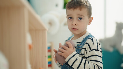 Adorable caucasian boy standing with relaxed expression at kindergarten