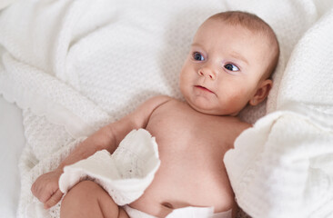 Adorable caucasian baby lying on bed with relaxed expression at bedroom