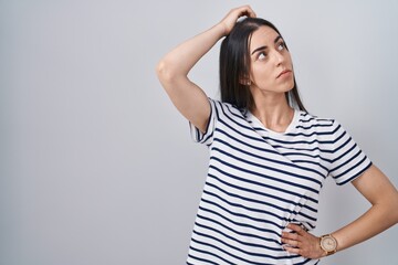Obraz premium Young brunette woman wearing striped t shirt confuse and wondering about question. uncertain with doubt, thinking with hand on head. pensive concept.