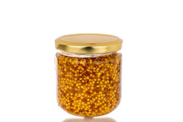 French mustard in a glass jar, macro, isolated on white background.