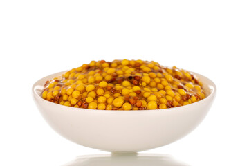 French mustard in white ceramic saucer, macro, isolated on white background.
