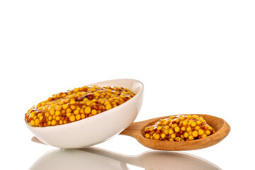 French mustard in white ceramic saucer with wooden spoon, macro, isolated on white background.