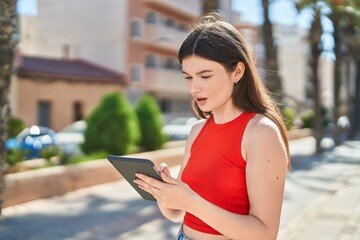 Fototapeta premium Young caucasian woman using touchpad with serious expression at park