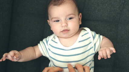 Adorable caucasian baby lying on sofa smiling for tickles at home