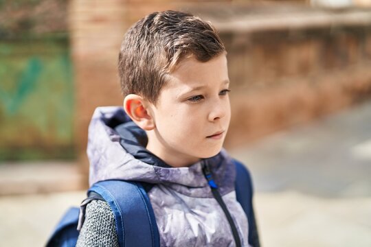 Blond child student standing with serious expression at street