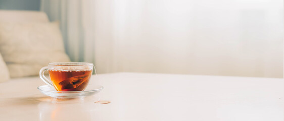 Glass cup with black tea from a tea bag on the table, home tea drinking. copy space, selective focus - obrazy, fototapety, plakaty