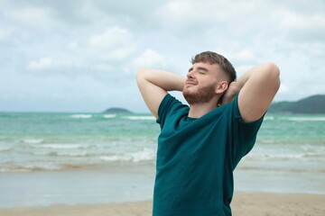 Happy guy, young handsome man is enjoying summer vacation at sea, beach in tropical exotic country, smiling, having fun