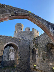 Fototapeta na wymiar Conwy, North Wales, United Kingdom: Conwy Castle fortification built by Edward I, during his conquest of Wales. Arch framing the Bakehouse Tower. Great room and chapel in the interior of castle.