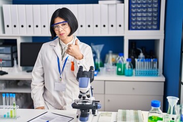 Young asian woman working at scientist laboratory smiling happy and positive, thumb up doing excellent and approval sign
