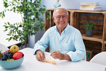 Fototapeta na wymiar Senior grey-haired man taking pills sitting on table at home