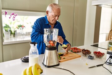 Senior man cutting avocado at kitchen