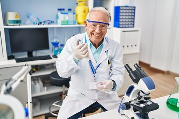 Senior man wearing scientist uniform using pipette working at laboratory