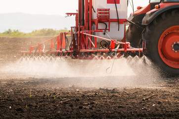 Fototapeta premium Tractor spraying land in sunset.