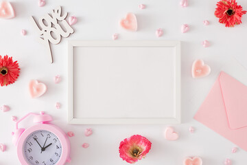 Women day concept. Flat lay photo of spring flowers, alarm clock, heart shaped candles, inscriptions love you, envelope on white background and frame in the middle. Mother's day Or Valentines idea.
